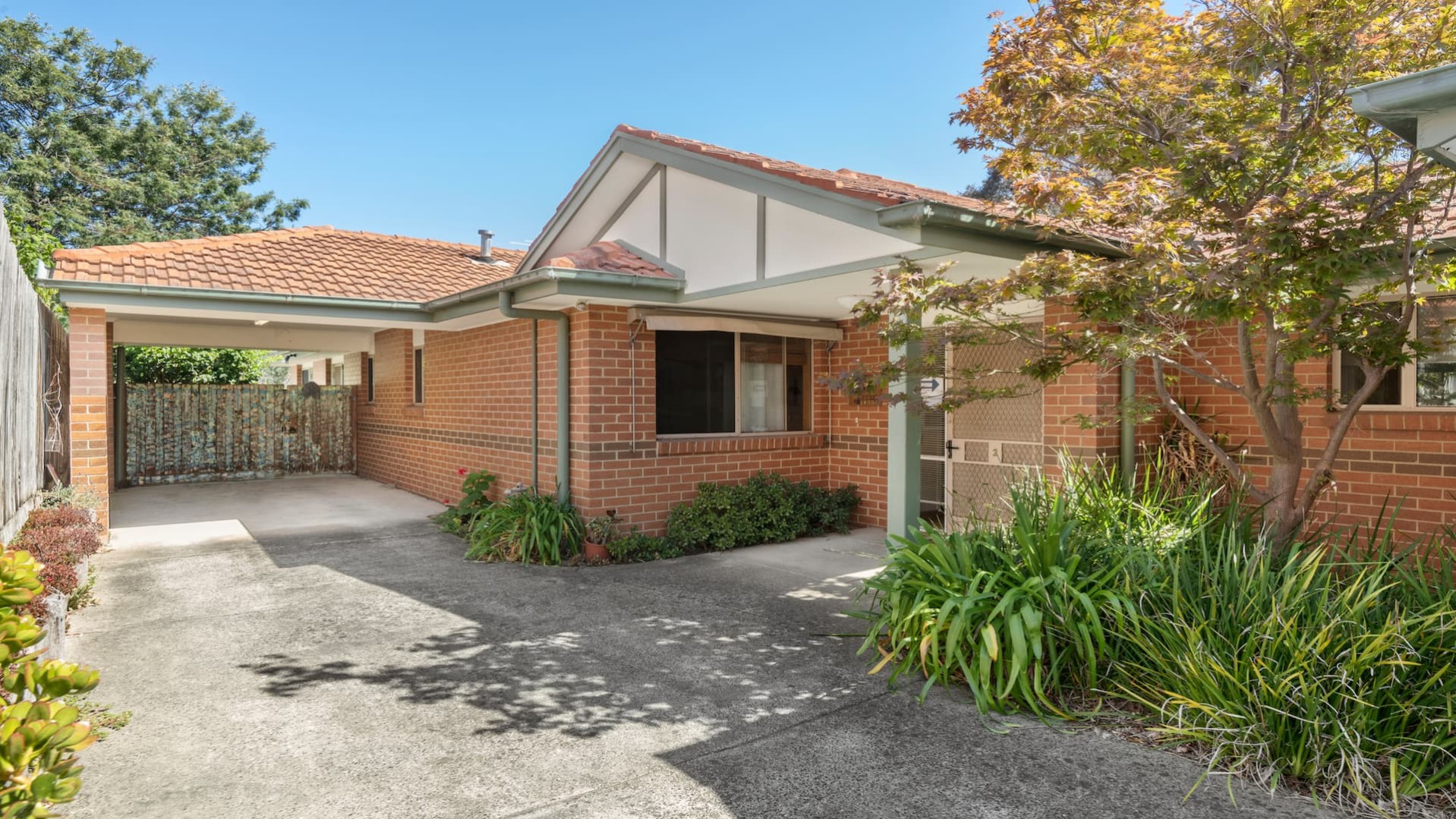 front of unit, with level concrete driveway and pathway, undercover parking.