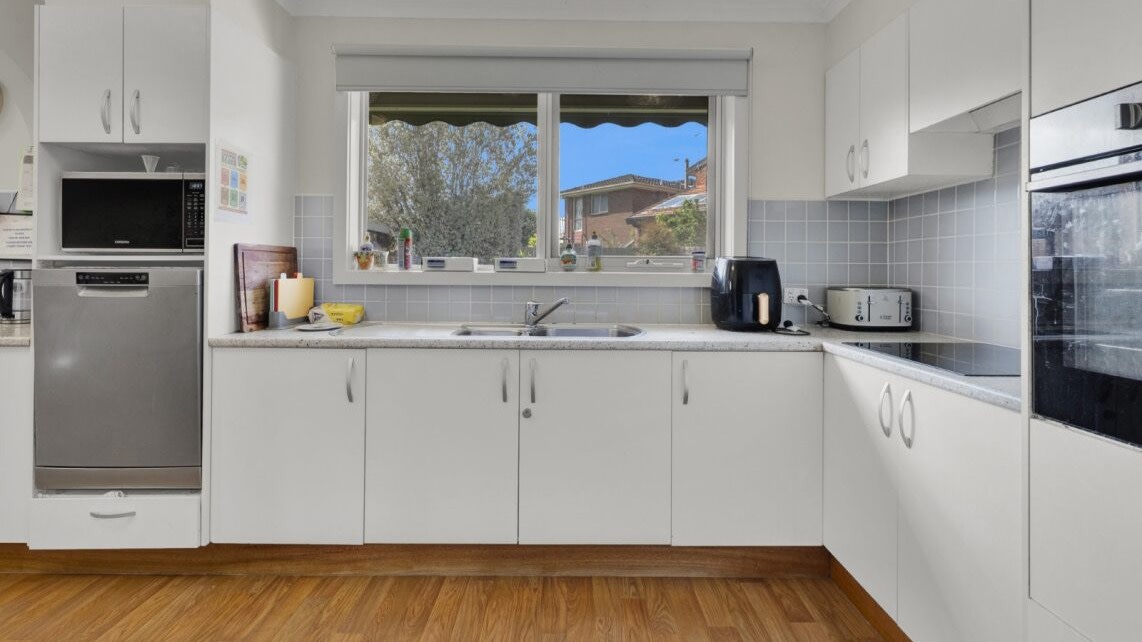 Kitchen with bench space, sink, appliances and window overlooking the yard.