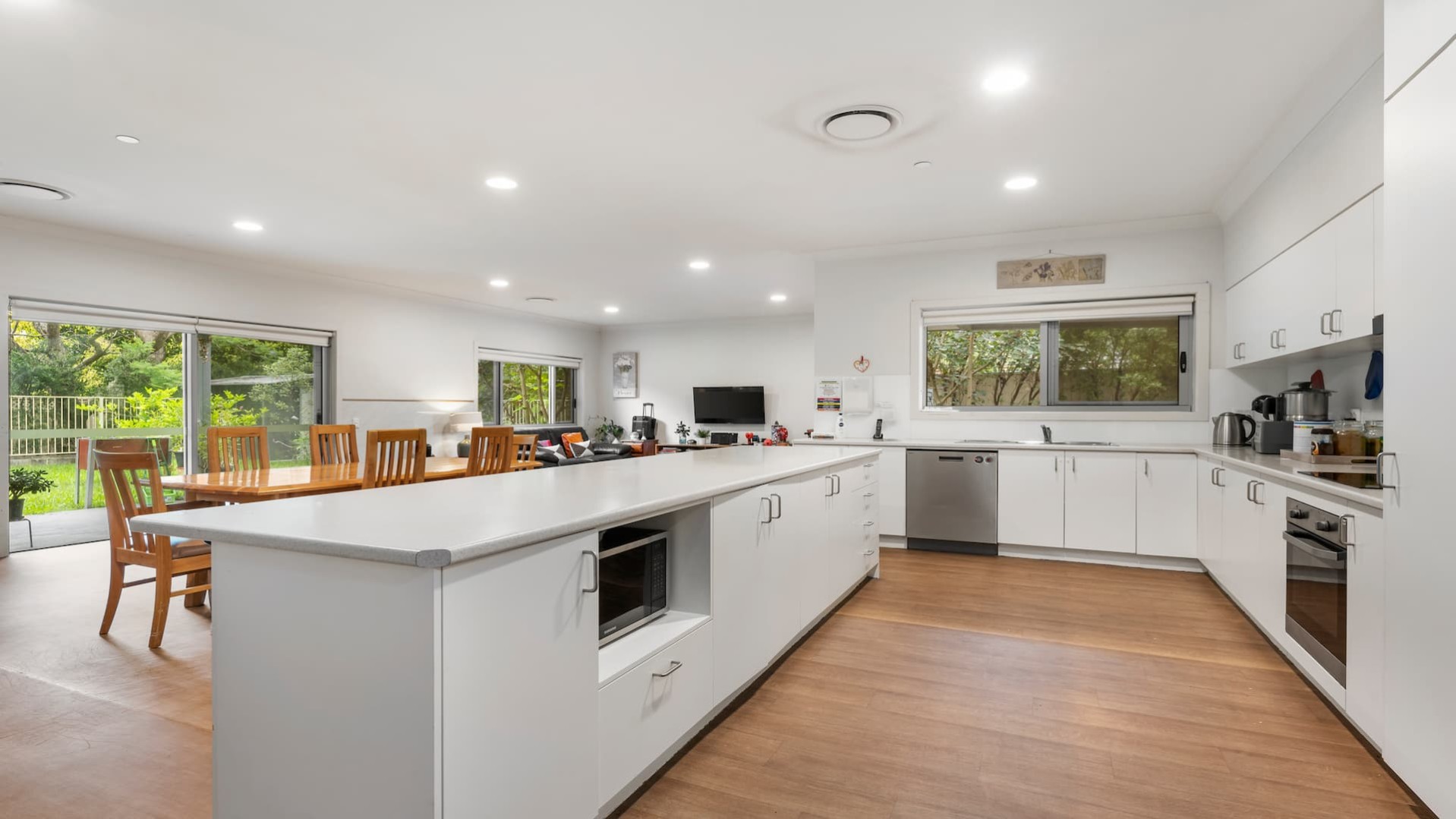 Kitchen with white benches and cabinets, structured in an L-shape with a large kitchen island.