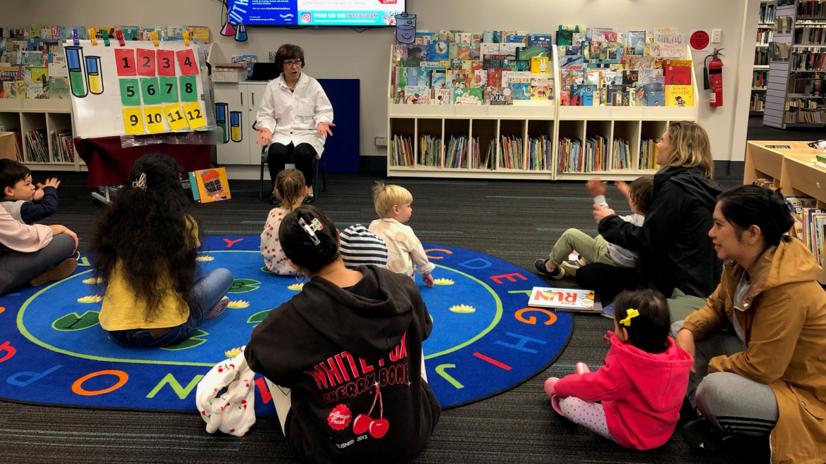 A librarian reading to children and adults at Sutherland Library.