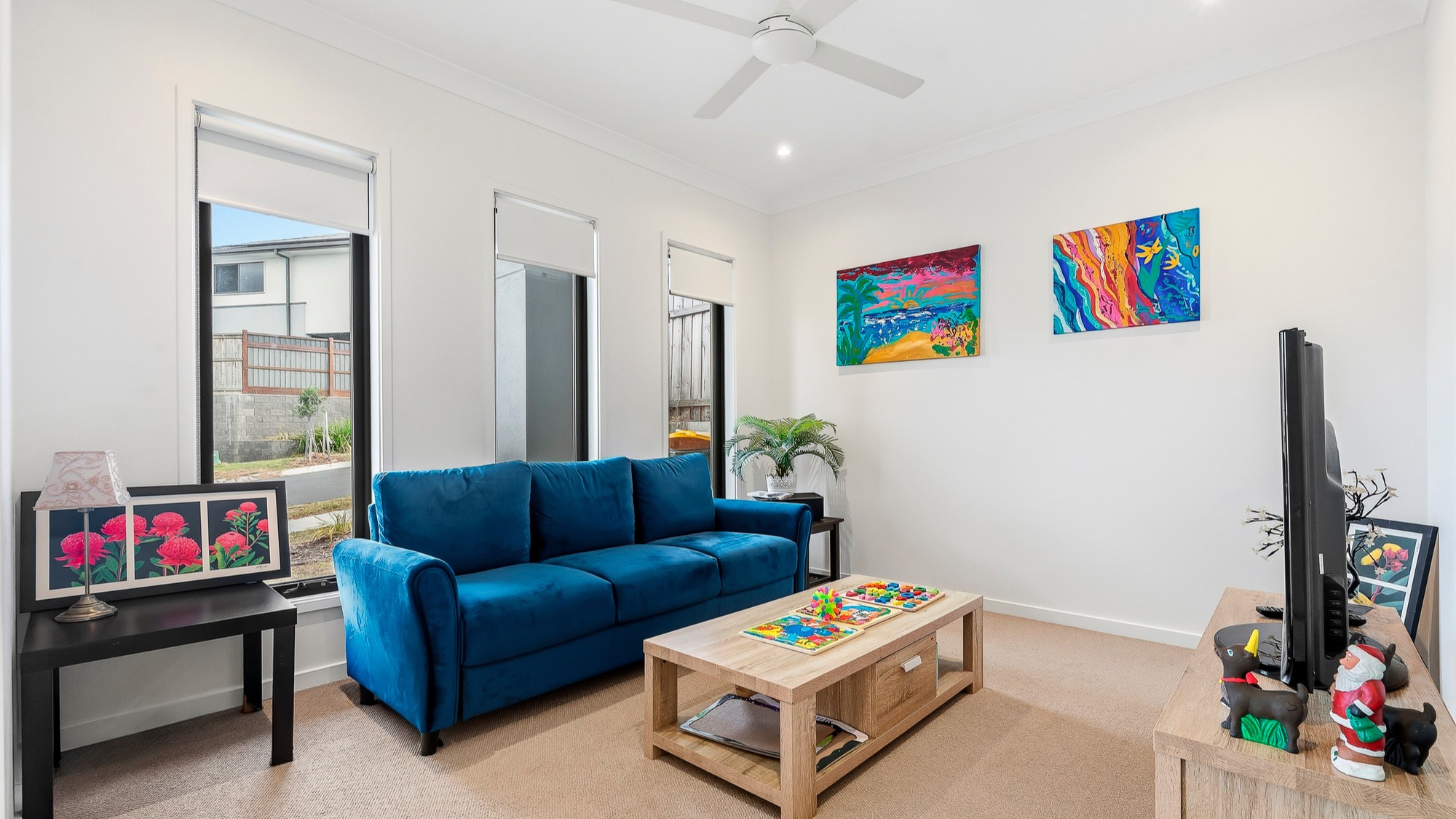 Second living room with a blue sofa, coffee table, TV unit and wall art.