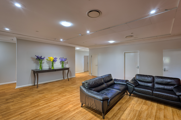 Loungeroom with two black couches and a dining table.