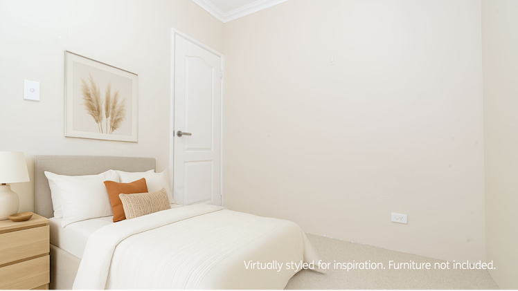 Bedroom with light walls, single bed with neutral bedding, wooden bedside table and lamp, featuring a framed botanical artwork and white door.