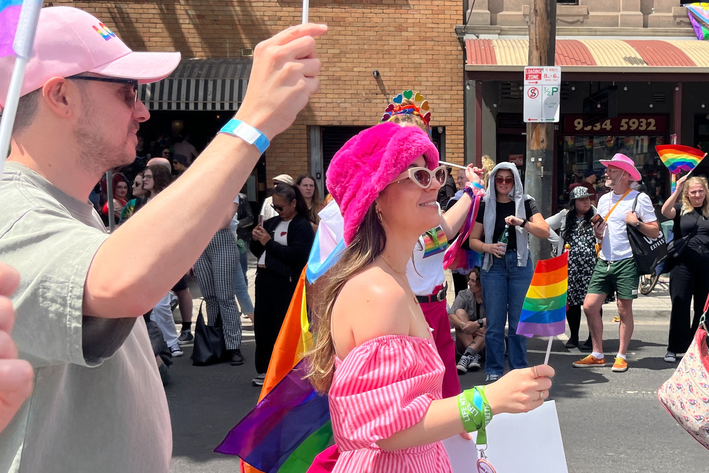 Jacintha Roberts wearing a pink dress and hat and holding a pride flag.