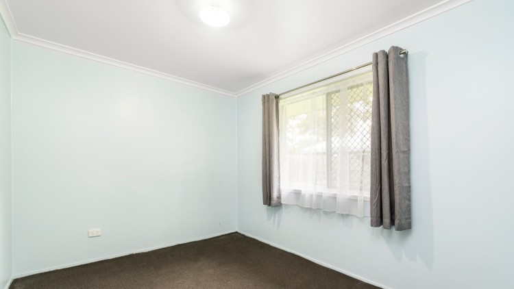 --Large carpeted bedroom with a curtained window.--