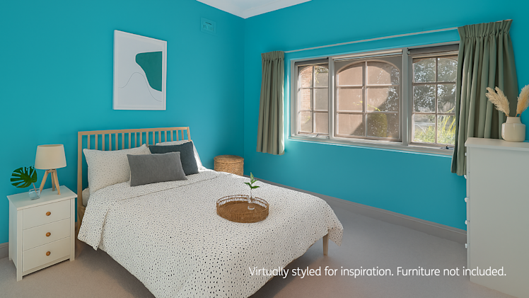 BedroomBright bedroom with turquoise walls featuring a wooden bed with black and white spotted bedding, a white bedside table with a lamp and plant, a white dresser with a vase of pampas grass, sage green curtains, and a large window with multiple panes.