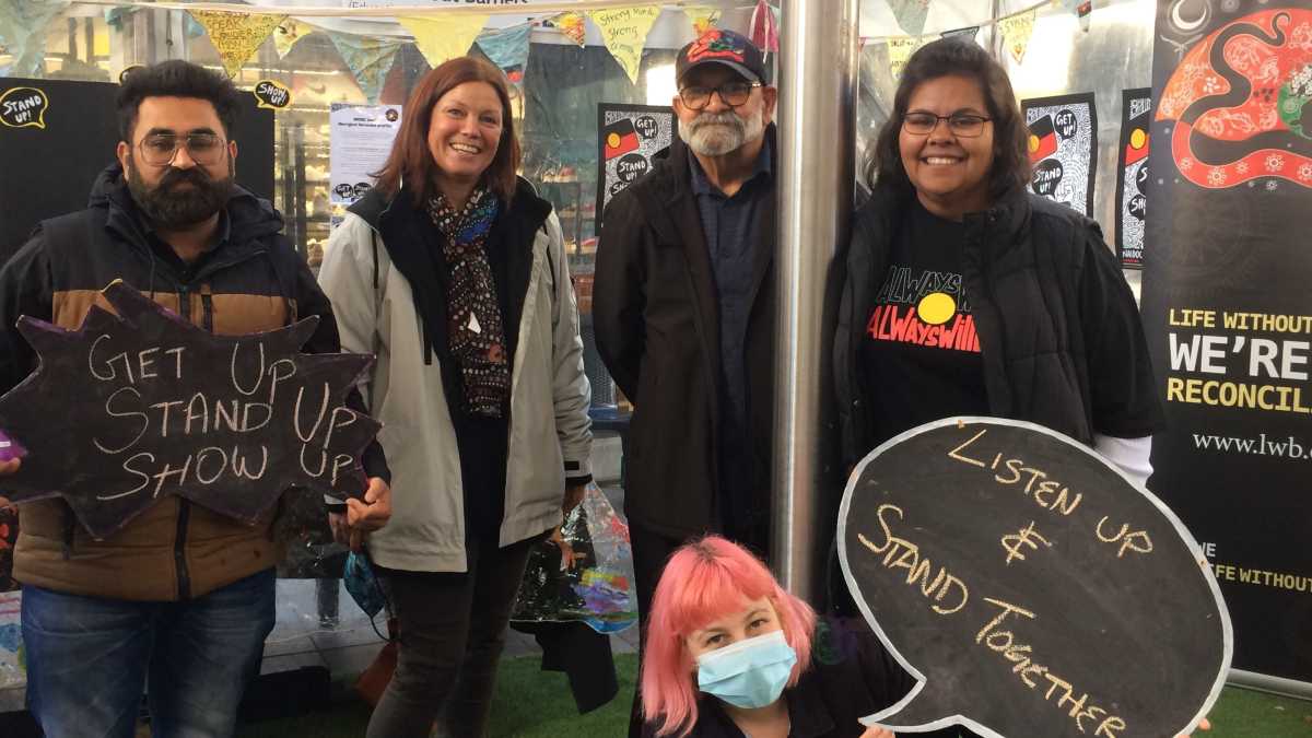 Life Without Barriers staff standing in a group in front of a stall at Rundel Mall NAIDOC week event.