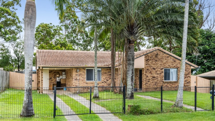 -- Front of home with palm trees, brick exterior, black fence.--