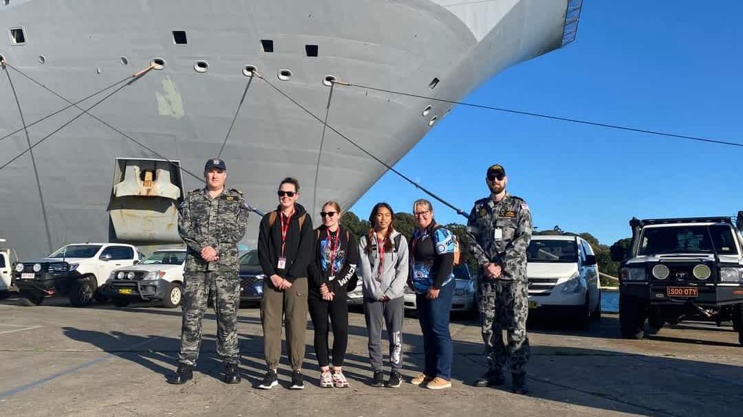 Ashley standing with two ADF officers and three other women in front of a ADF ship.