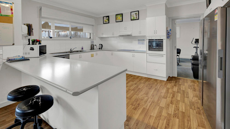 Large kitchen with white cabinets, ample bench and storage space.