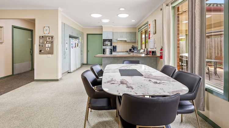 Open-plan kitchen and dining area with island bench, dining table and natural light.