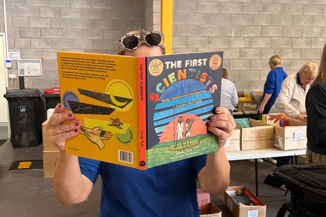 An individual holds a picture book over their face.