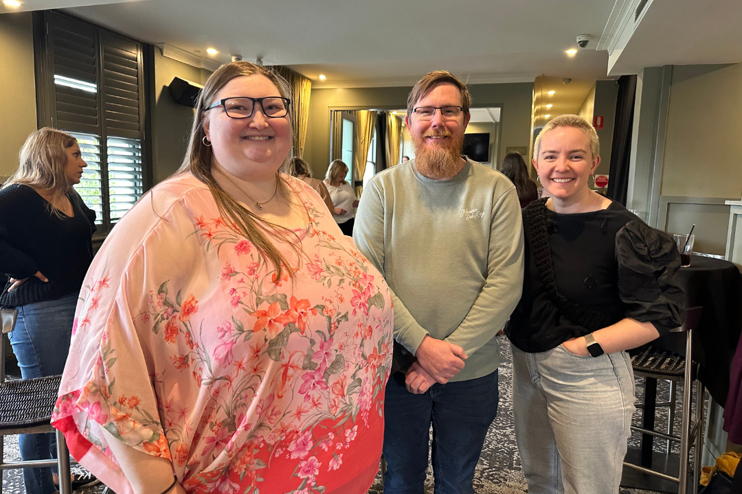 Three carers standing as a group, smiling at the camera.