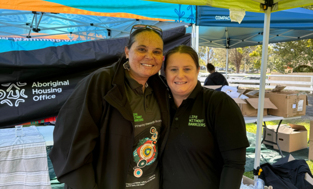 Two staff members wearing Life Without Barriers RAP shirts at the Shoalhaven NAIDOC event. 