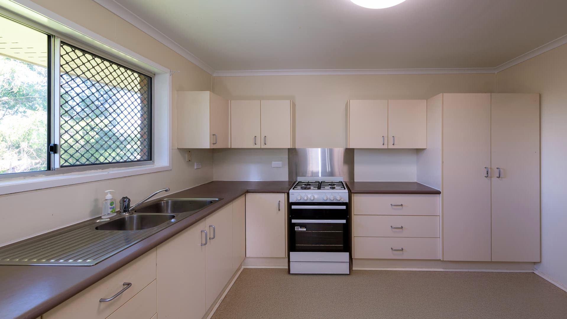 --Kitchen with L-shaped bench, cream cabinets, and an oven/stove unit.--