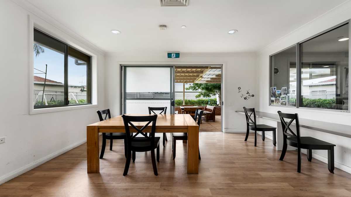 Dining area with a wooden table and chairs, and a bench running the length of the wall to the right.