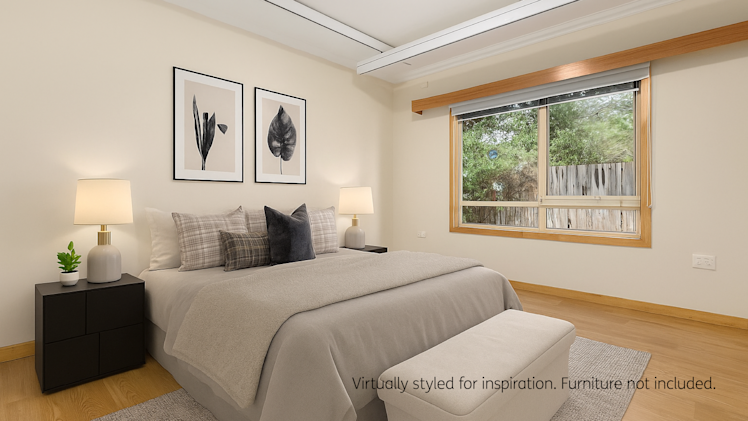 Stylish bedroom with a queen bed featuring neutral bedding and accent pillows, two black bedside tables with modern lamps, framed botanical artwork on the wall, a light grey rug, and a storage bench at the foot of the bed; large window with wooden trim allows natural light to fill the room.