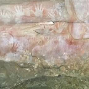Close up of the wall in Red Hands Cave with white handprints in the red rock