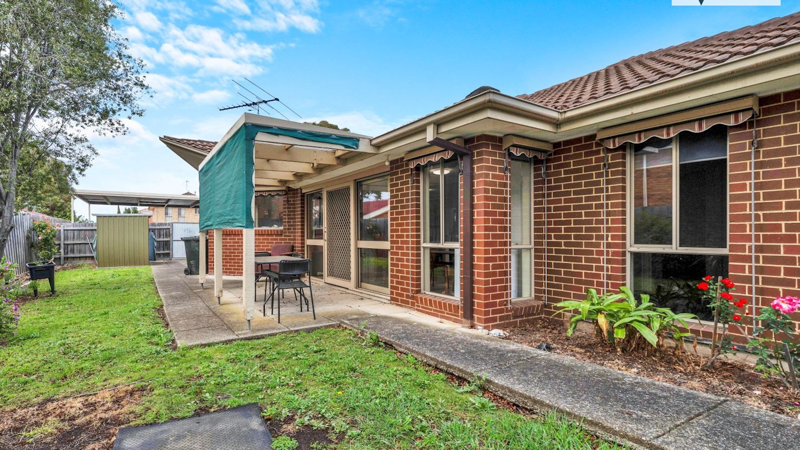 Outdoor patio and backyard with seating area, lawn, garden beds, and accessible pathways around the home.