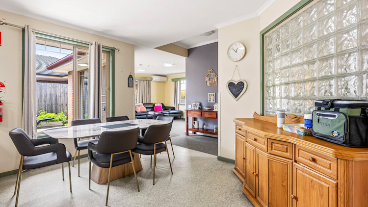 Open-plan dining and living area with table, seating and natural light.