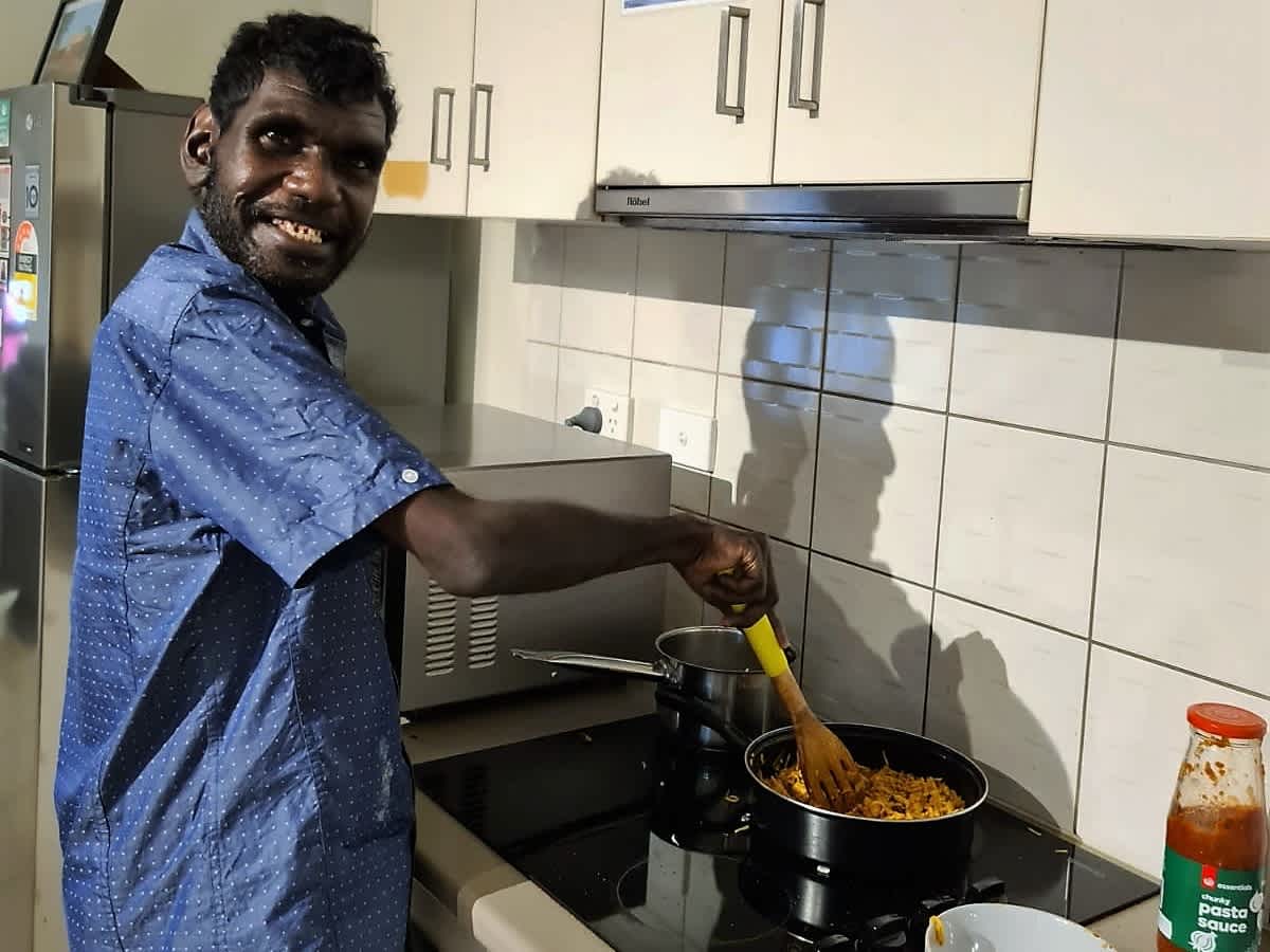 Warren in a blue shirt cooking food on the stove