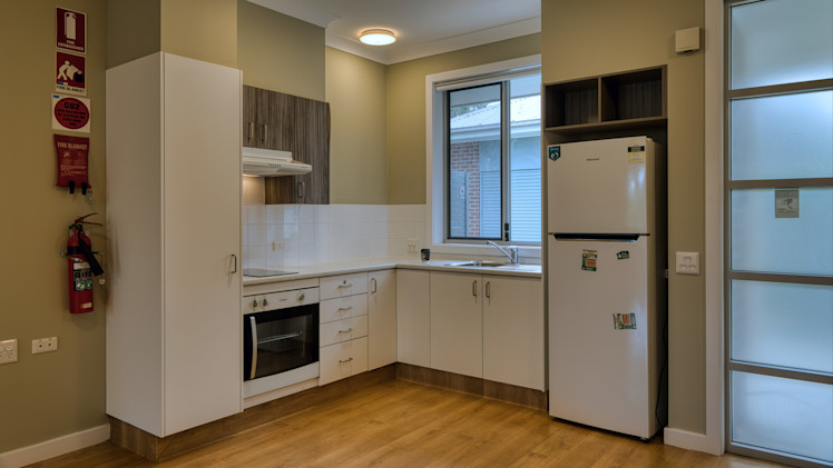 Kitchen with bench space, storage, an oven, fridge, and wooden floors.