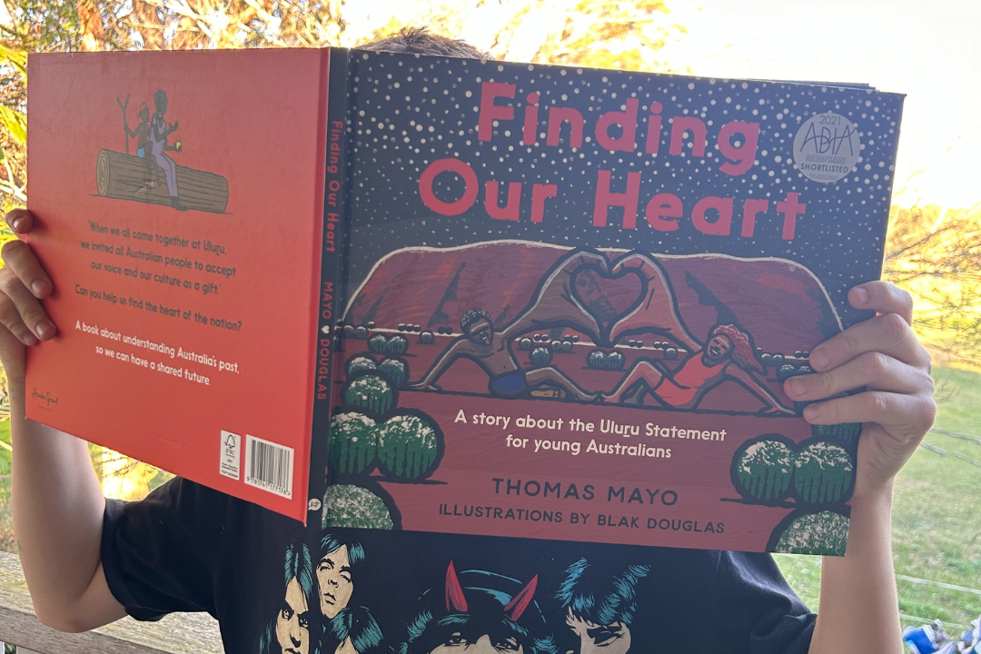 An individual holds a picture book over their face.