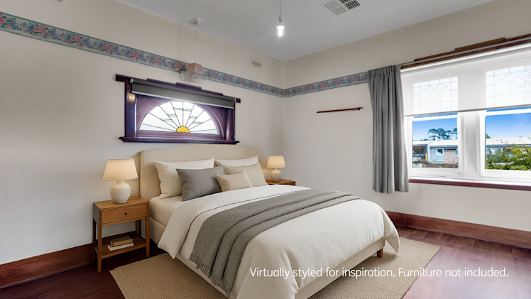 beautifully presented spacious bedroom with stained glass window, wooden free standing wardrobe, bed, side table and armchair.