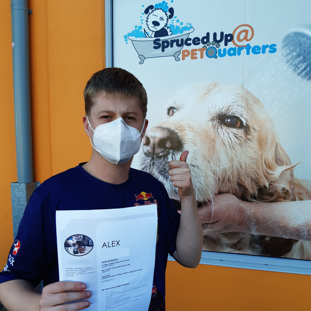 Alex holding a certificate standing in front of a sign with an image of a dog.
