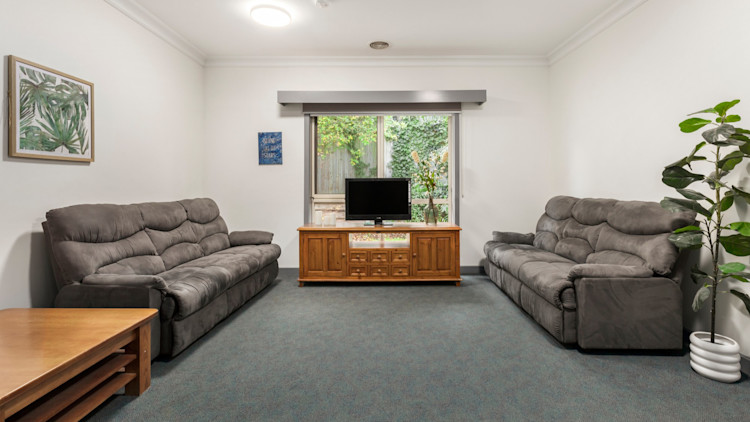Loungeroom with two grey couches, a TV on a stand and a coffee table.