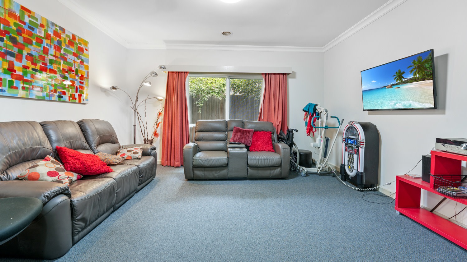 Comfortable lounge room with recliner sofas, wall-mounted TV and soft lighting.