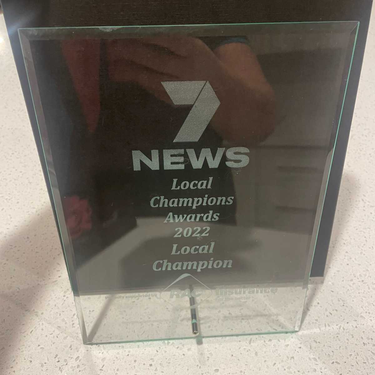 Close up of the award which is made of clear glass with text engraved that reads: 7 News Local Champions Awards 2022 Local Champion.
