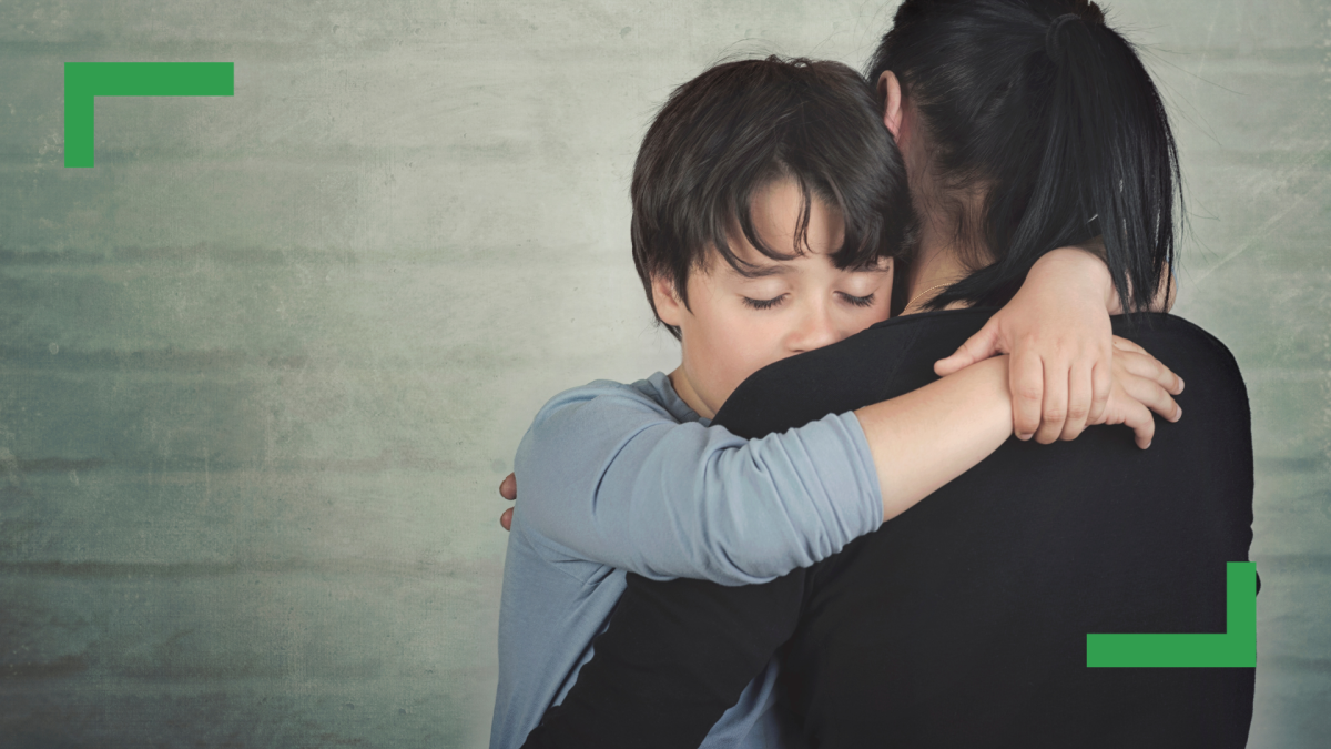 A young boy wearing a blue shirt is hugging a woman with brown hair wearing a black shirt.