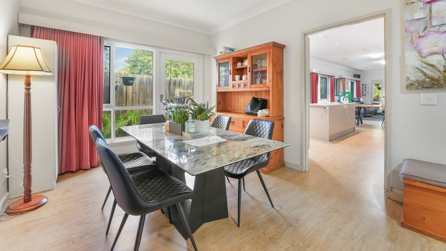 Dining room with table and chairs, timber cabinet, and natural light.