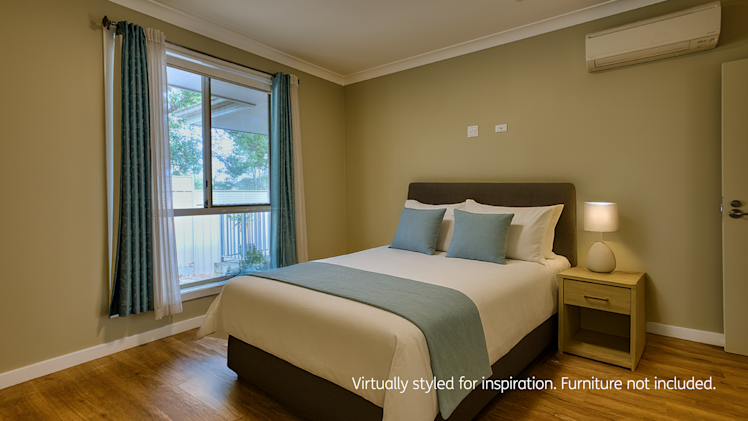 Cozy bedroom with green-toned walls, wood flooring, teal accents, a single bedside table, and large window with drapes.