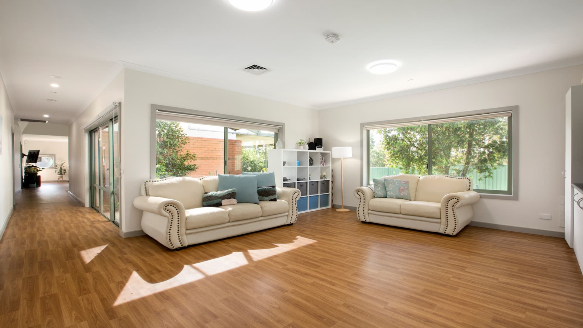 Lounge room with two cream couches and a 4x4 cube shelf.