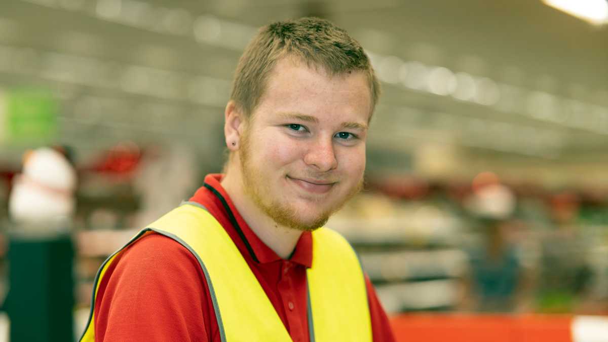 Jayden wearing a Coles red polo and yellow high-vis vest.
