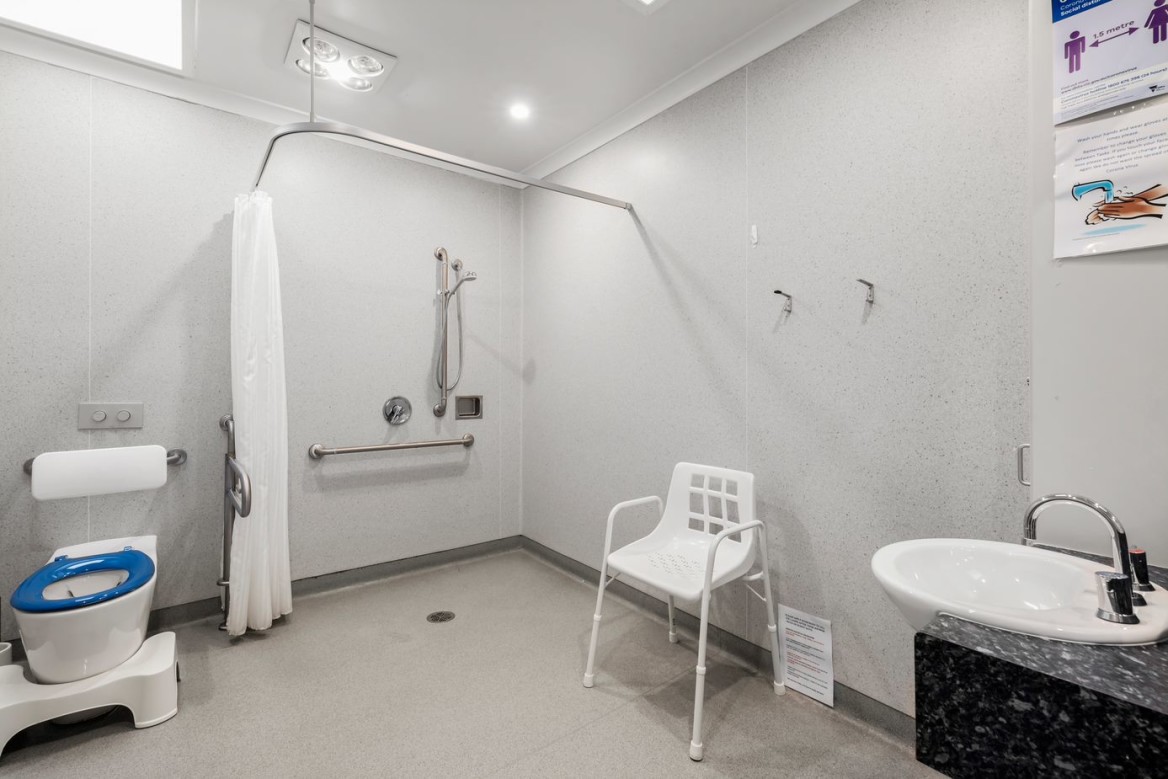 --Bathroom with toilet, shower, sink, shower chair and handrails.--