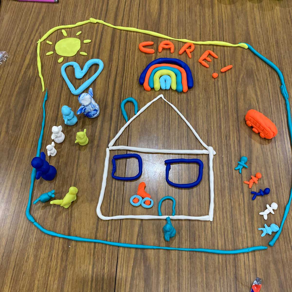 Staff created a visual to represent care from playdough of a house with human figures, a heart, a sun and the word CARE.
