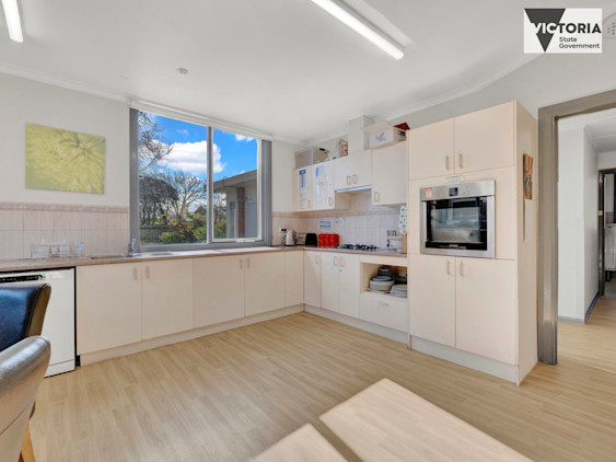 Modern kitchen with cream cabinets, built-in oven, gas cooktop, dishwasher, and large window overlooking garden