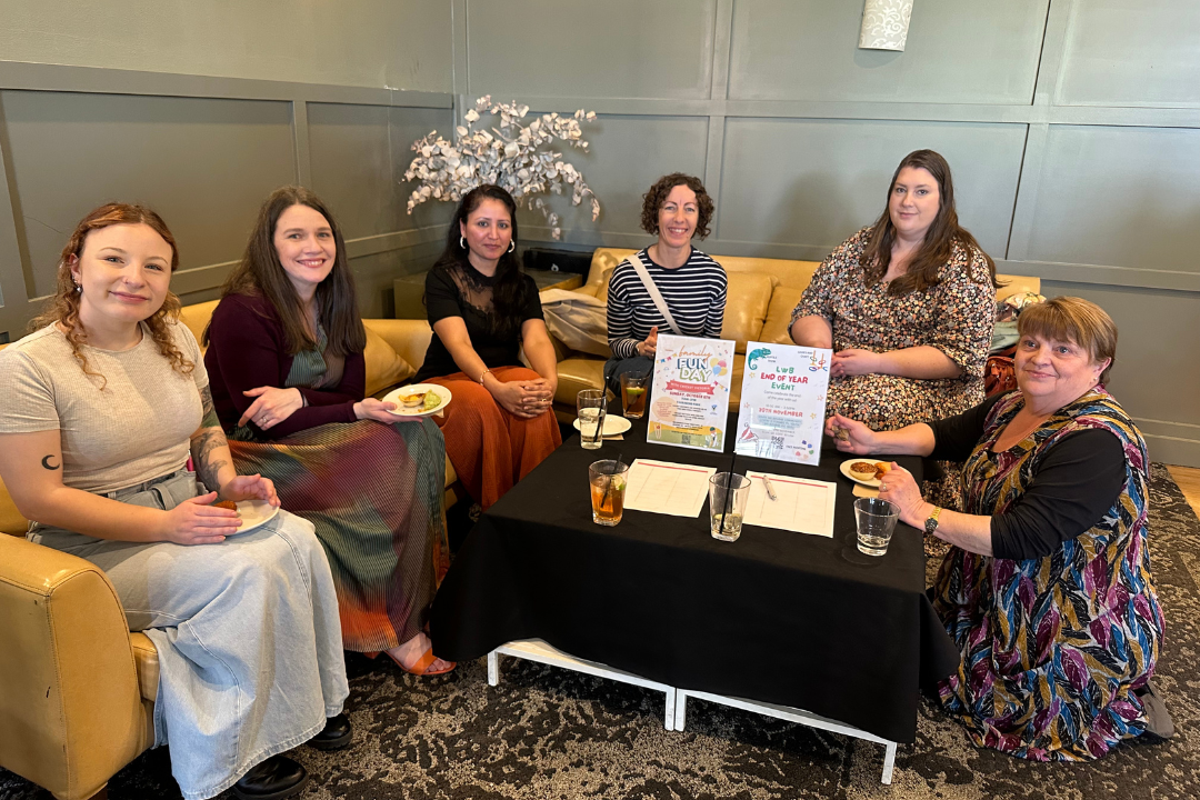 Staff and carer sitting on couches, smiling at the camera.