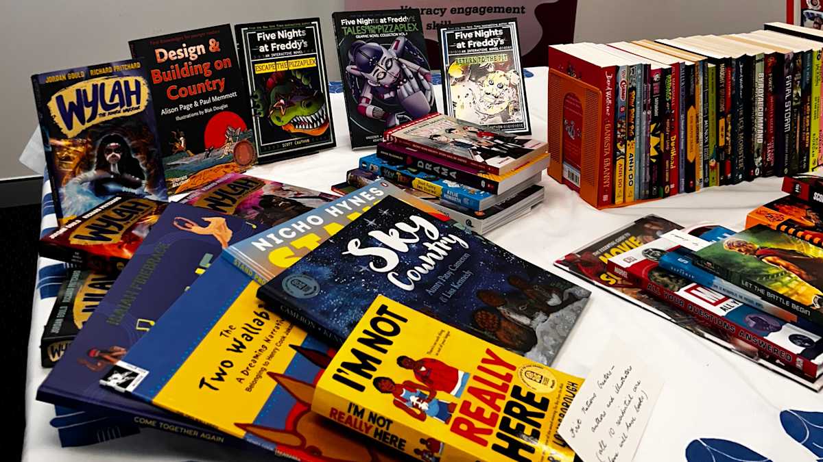 A table with books on display on top of a table cloth with the the Children’s Book Council of Australia logo.
