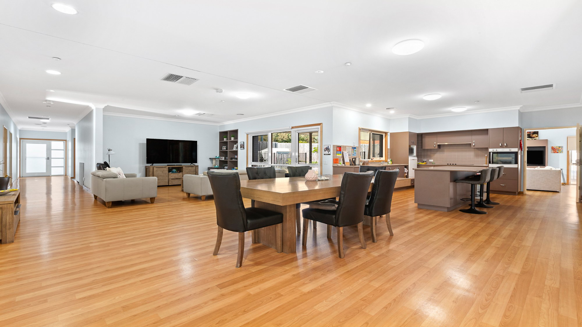 --View of open plan living area which includes dining table, lounge area and kitchen.--