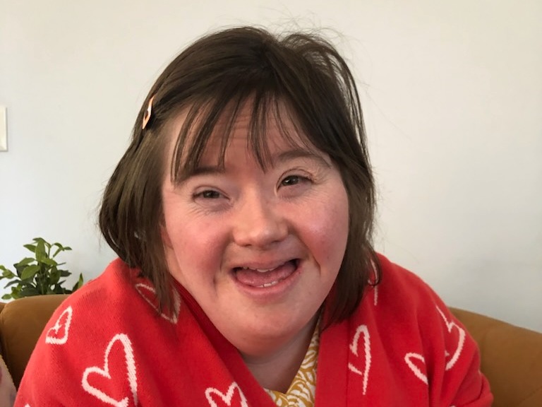 Livvy is wearing a red cardi with white hearts. She has short brown hair. 