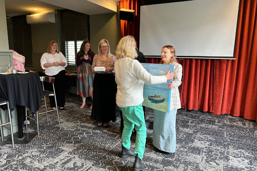 Ruby, staff, presenting Elaine, carer, with a painting.