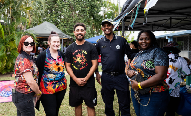 A group of staff and attendees smile at the camera at the TAIHS NAIDOC event.