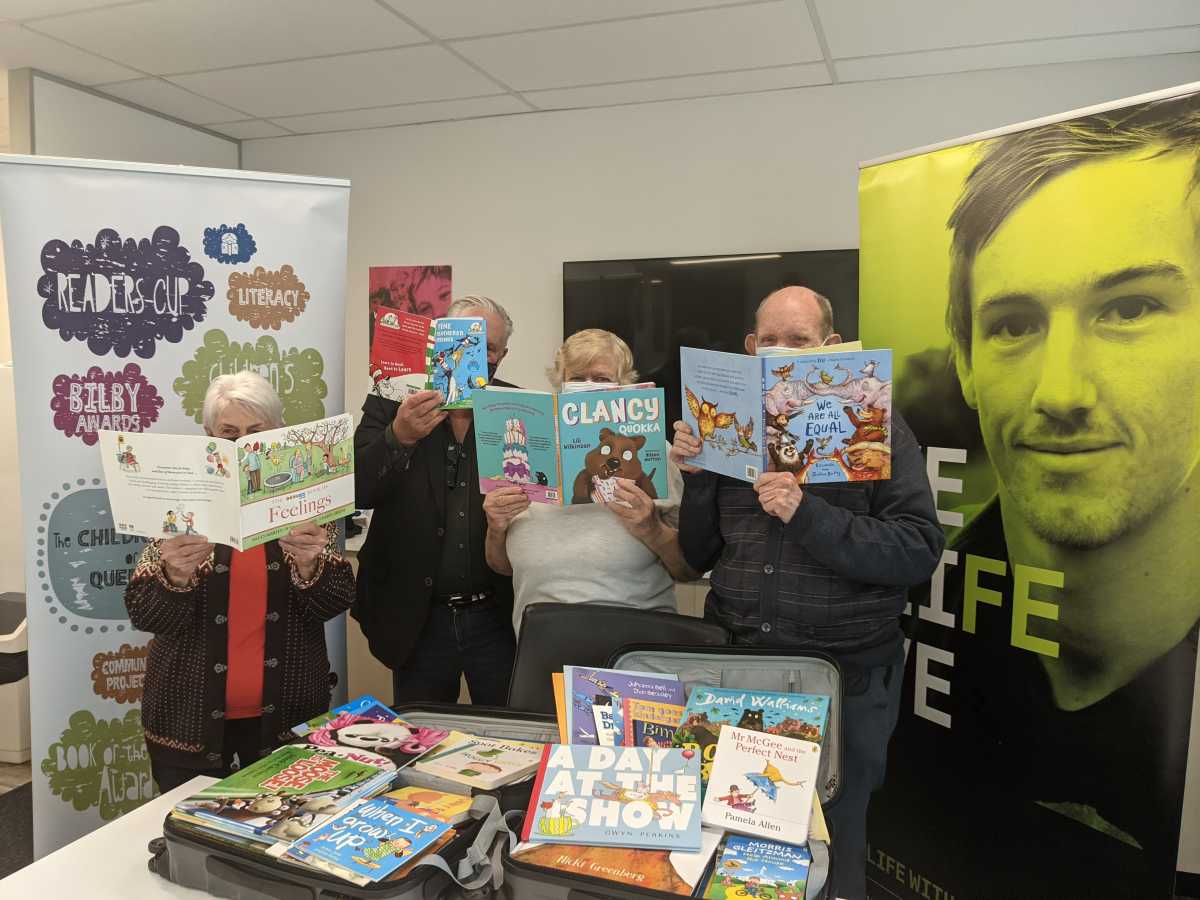 Children's Book Council, QLD Branch. Four adults holding books covering their faces.