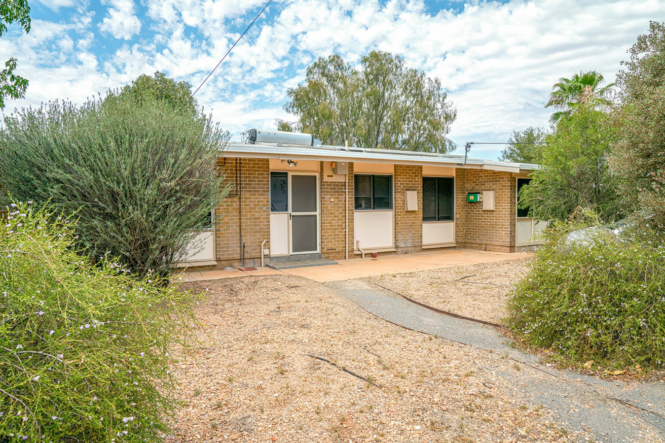 --Outside Araluen property with path to front door and bushes.--