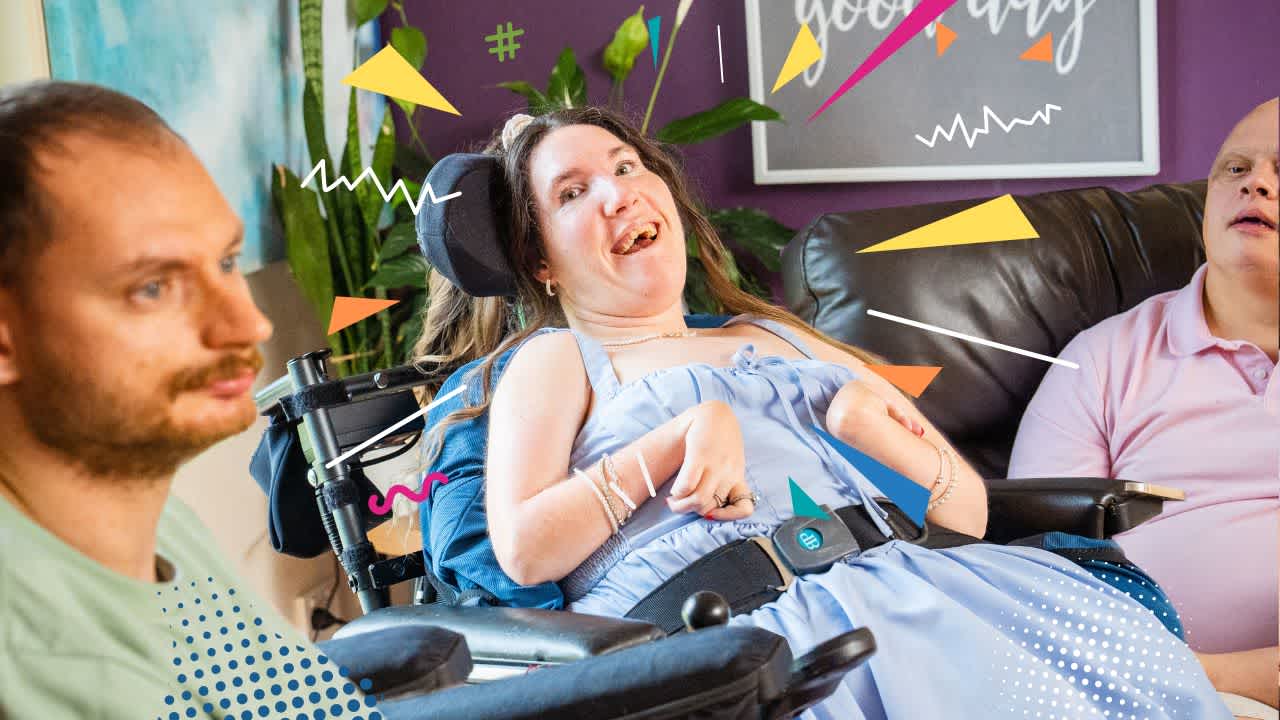 A women wearing a blue dress suits in a wheelchair and smiles at the camera.