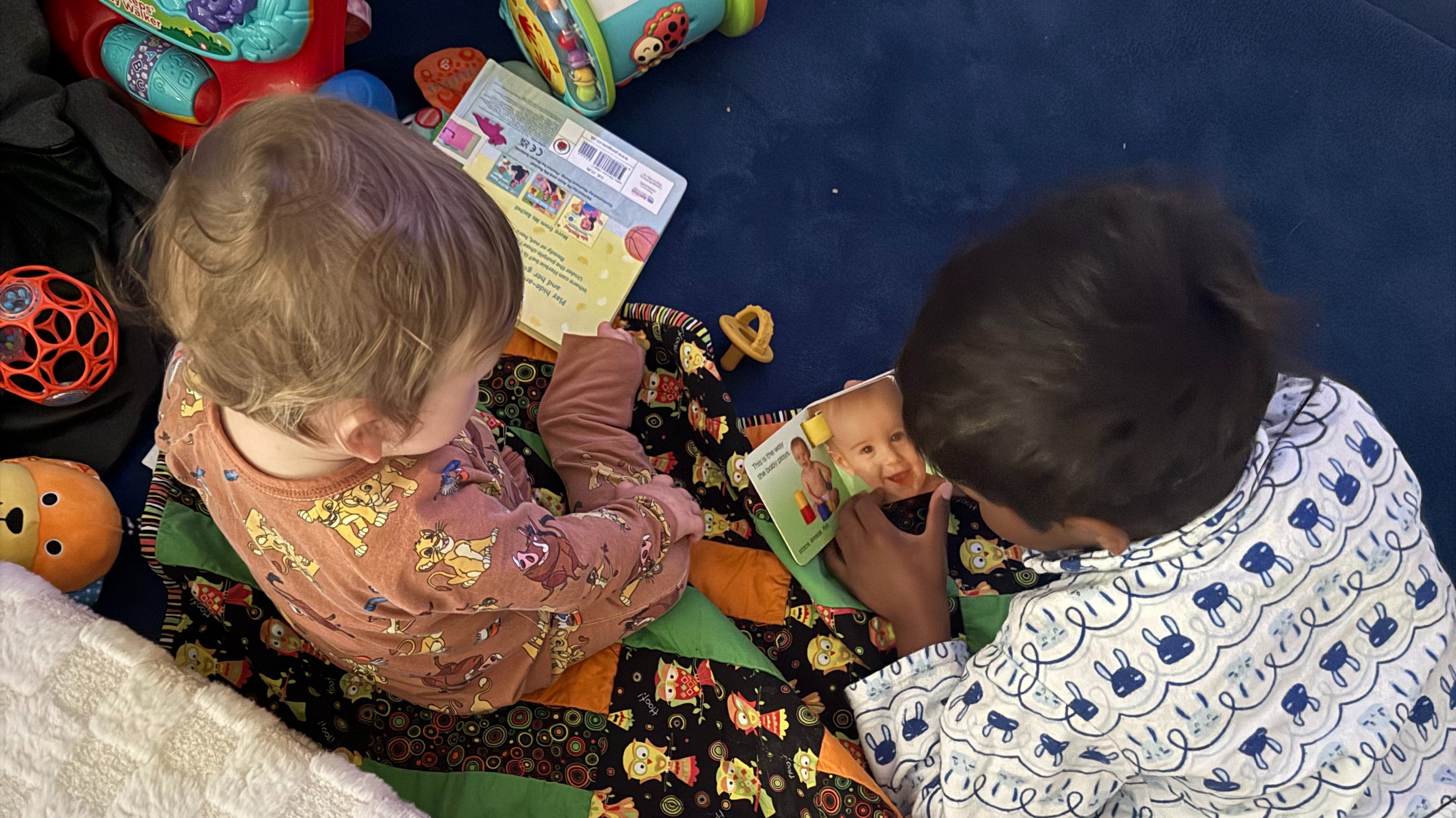 Birds-eye-view of two young people sitting on the floor, reading books together.